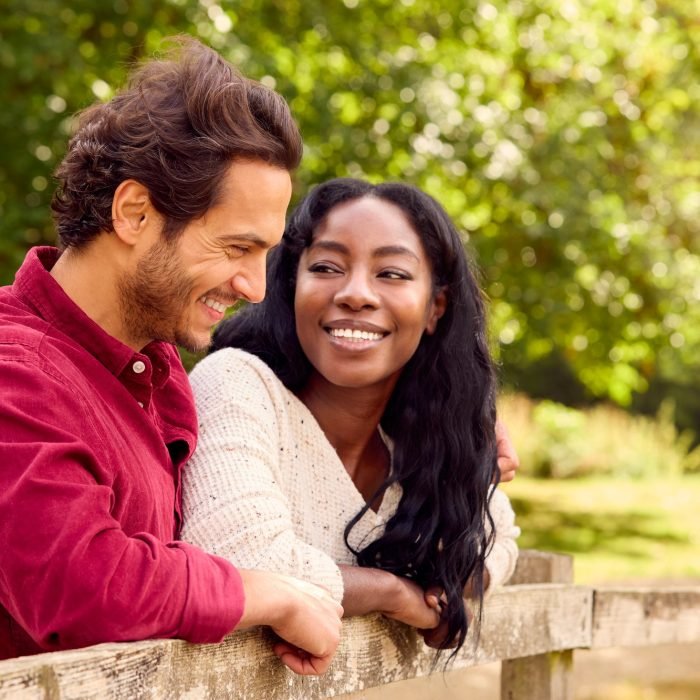 Loving Mixed Race Couple Leaning On Fence On Walk In Countryside Loving Mixed Race Couple Leaning On Fence On Walk In Countryside