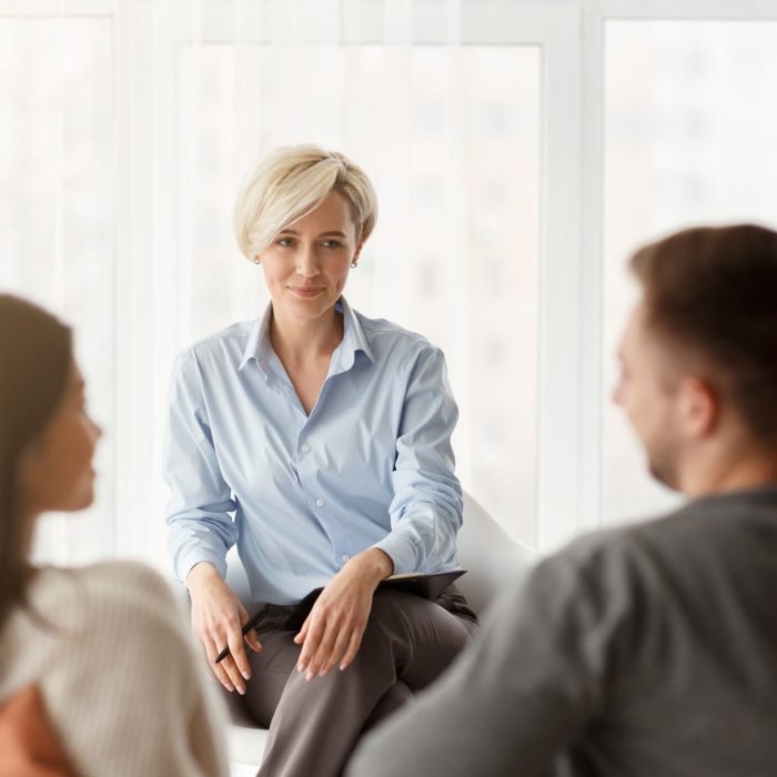 Psychologist Smiling Looking At Couple's Reconciliation Sitting In Office Psychologist Smiling Looking At Couple's Reconciliation Sitting In Office